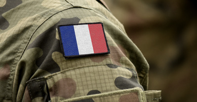 Écusson du drapeau français tricolore cousu sur la manche d'un uniforme militaire camouflage.