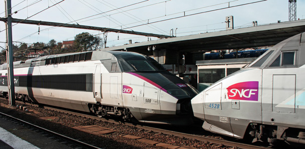 Deux TGV SNCF aux couleurs blanc et rose stationnés côte à côte en gare, sous les caténaires, avec les numéros de rames 508 et 4528 visibles.